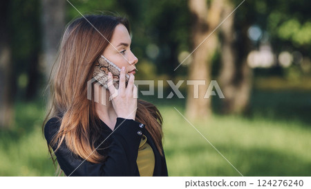 Professional woman talking confidently on mobile phone, sitting amid lush greenery during sunny workday break Professional woman talking confidently on mobile phone, sitting amid lush greenery during sunny workday break 124276240