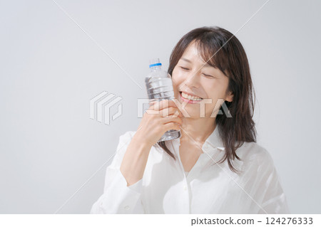 A woman drinking water with a smile A woman drinking water with a smile 124276333