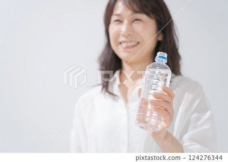 A woman drinking water with a smile A woman drinking water with a smile 124276344
