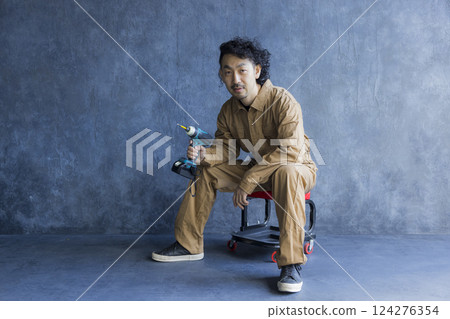 A man in overalls sitting on a work chair 124276354