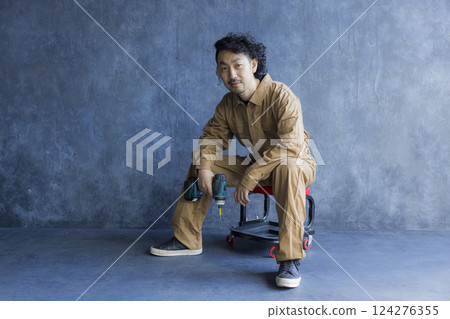 A man in overalls sitting on a work chair 124276355