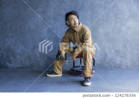A man in overalls sitting on a work chair 124276356