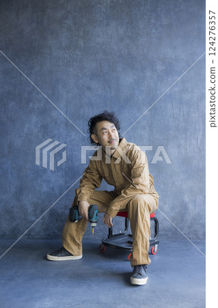 A man in overalls sitting on a work chair 124276357