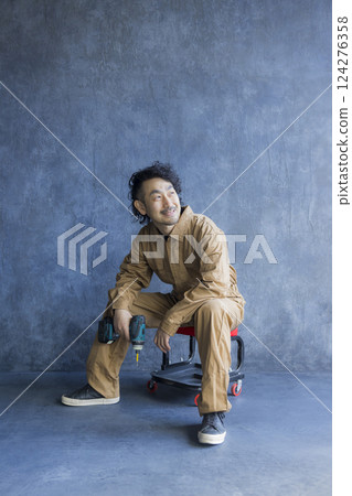 A man in overalls sitting on a work chair 124276358
