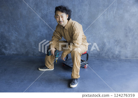 A man in overalls sitting on a work chair A man in overalls sitting on a work chair 124276359