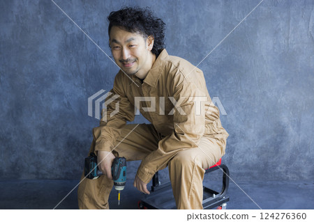 A man in overalls sitting on a work chair A man in overalls sitting on a work chair 124276360