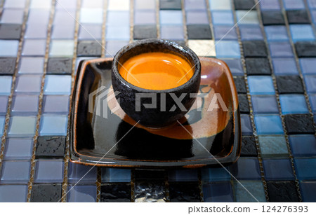 An espresso shot serving in classic black ceramic cup on amulticolored crystal backgrounds. An espresso shot serving in classic black ceramic cup on amulticolored crystal backgrounds. 124276393