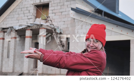 Female architect presenting house blueprint, pointing confidently while standing near construction site model Female architect presenting house blueprint, pointing confidently while standing near construction site model 124276402