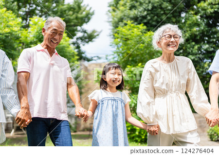 Senior couple walking hand in hand with their grandchild 124276404