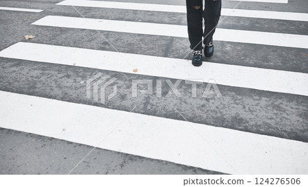 Young woman walking across street, black denim pants and leather boots during fall season Young woman walking across street, black denim pants and leather boots during fall season 124276506