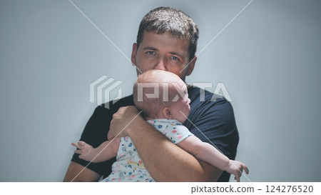 Serious looking father holding newborn infant, expressing deep emotional connection and paternal protectiveness Serious looking father holding newborn infant, expressing deep emotional connection and paternal protectiveness 124276520