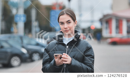 Young professional texting while navigating busy downtown sidewalk, embodying modern mobile lifestyle 124276528