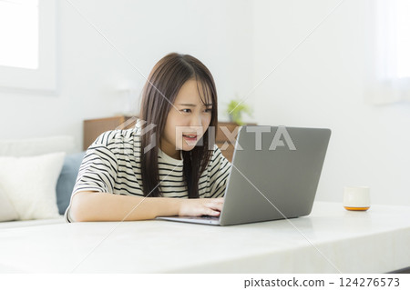 Young woman using a computer in the living room 124276573