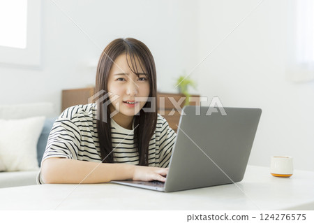 使用一台電腦在客廳裡的年輕女子 124276575