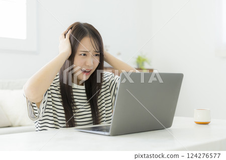 使用一台電腦在客廳裡的年輕女子 124276577