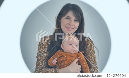 Loving mother cradling newborn, soft ring light enhancing warm connection between parent and infant Loving mother cradling newborn, soft ring light enhancing warm connection between parent and infant 124276604