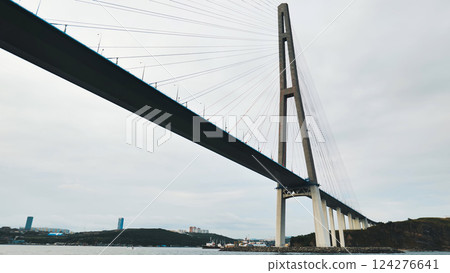 Modern cable stayed bridge dominating seascape, connecting landmasses under a cloudy sky, showcasing strength and elegance in infrastructure design Modern cable stayed bridge dominating seascape, connecting landmasses under a cloudy sky, showcasing strength and elegance in infrastructure design 124276641