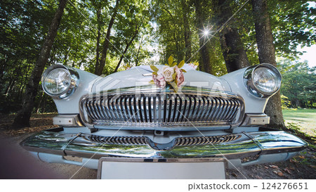 White vintage car decorated with a bouquet of flowers standing in a park, ready for a wedding ceremony 124276651