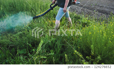 Farmer spraying herbicide on weeds growing in field Farmer spraying herbicide on weeds growing in field 124276652