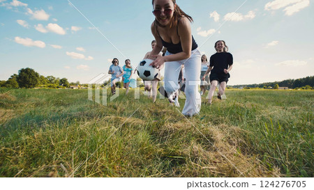 Happy high school students running with soccer ball in summer field, enjoying their leisure time during holidays Happy high school students running with soccer ball in summer field, enjoying their leisure time during holidays 124276705