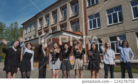 Happy students bid farewell outside their high school building on a beautiful, sunny day 124276750