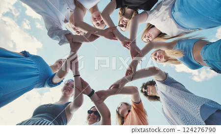 School friends come together in a circle, showcasing unity, teamwork, and collaboration under a clear sky 124276790