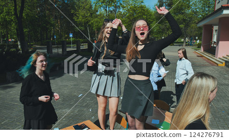 Group of cheerful female students celebrating the end of school year, dancing and having fun outdoors Group of cheerful female students celebrating the end of school year, dancing and having fun outdoors 124276791