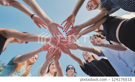 Group of friends forming a circle joining hands together outdoors in a sunny day. Group of friends forming a circle joining hands together outdoors in a sunny day. 124276818