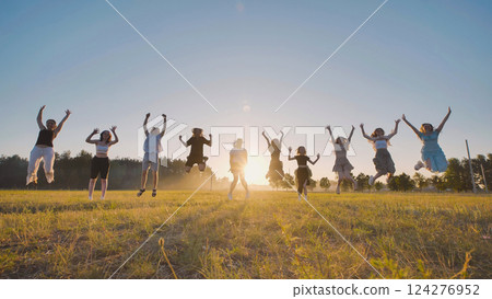 Group of joyful high school students jumping with raised arms in a field at sunset, celebrating summer holidays Group of joyful high school students jumping with raised arms in a field at sunset, celebrating summer holidays 124276952