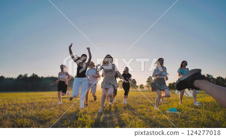 Cheerful high school students running in a field at sunset, having fun during their summer break Cheerful high school students running in a field at sunset, having fun during their summer break 124277018
