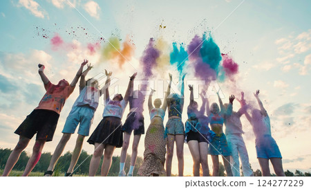 School friends joyfully tossing colorful powder in the air at sunset, commemorating their friendship and making lively memories 124277229