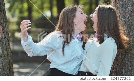 Two young female professionals in bow ties having a heated argument and yelling at each other in a park 124277261