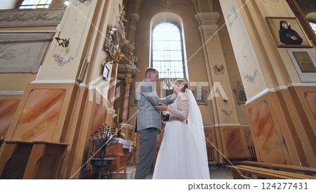 Bride and groom exchanging emotional wedding vows, sharing intimate moment inside elegant church sanctuary 124277431