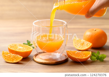 Orange juice pouring into glass with orange fruit on wooden background, Healthy drink 124278376