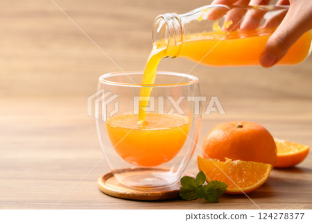Orange juice pouring into glass with orange fruit on wooden background, Healthy drink 124278377