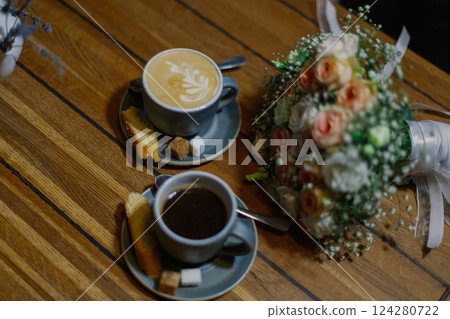 Two cups of coffee stand on a wooden table and a Two cups of coffee stand on a wooden table and a 124280722