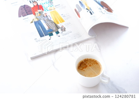 這張照片是在白色桌子上一邊喝著用濃縮咖啡和牛奶製成的拿鐵咖啡一邊閱讀雜誌的照片。 這張照片是在白色桌子上一邊喝著用濃縮咖啡和牛奶製成的拿鐵咖啡一邊閱讀雜誌的照片。 124280781