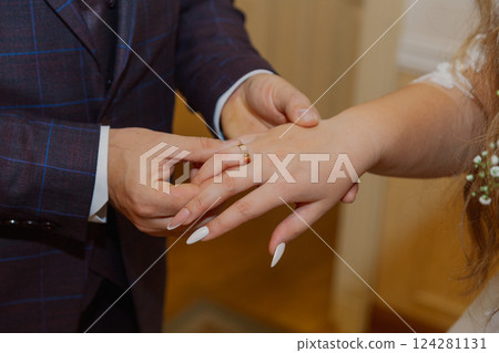 A young groom puts a gold wedding ring on his 124281131