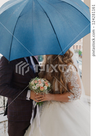 Happy newlyweds take shelter under an umbrella and 124281161