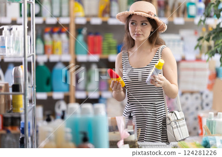 Young woman choosing repellent in household chemicals store Young woman choosing repellent in household chemicals store 124281226