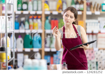 Young female salesperson makes notes on an electronic tablet - keeps track of the receipt and expenditure of goods in supermarket Young female salesperson makes notes on an electronic tablet - keeps track of the receipt and expenditure of goods in supermarket 124281252