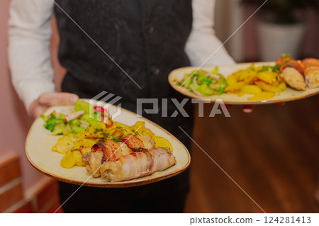 Waiter holding a plate of food in his hands in a Waiter holding a plate of food in his hands in a 124281413