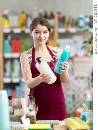 Sales girl places shampoo and shower gel on the shelves of supermarket Sales girl places shampoo and shower gel on the shelves of supermarket 124281418