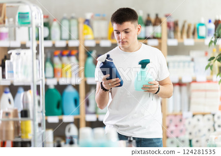 Young man chooses cleaning spray in store 124281535