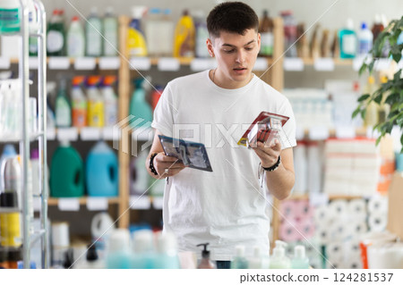 Man carefully selects razor for shaving in the household goods department of supermarket Man carefully selects razor for shaving in the household goods department of supermarket 124281537
