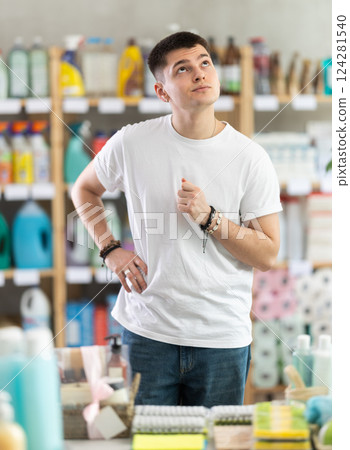Young man chooses household chemicals in store Young man chooses household chemicals in store 124281540