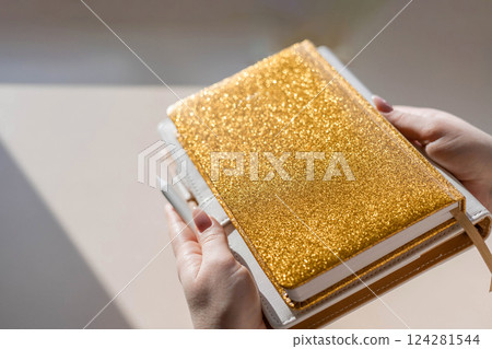 Gold colored diary, pen on bright background. New year planning concept. Minimalistic workstation. 124281544