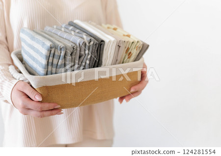 Female hands close up hold wicker stylish natural basket with pillowcases and bed linen. Female hands close up hold wicker stylish natural basket with pillowcases and bed linen. 124281554