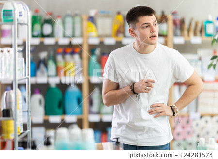 Young man chooses household chemicals in store 124281573