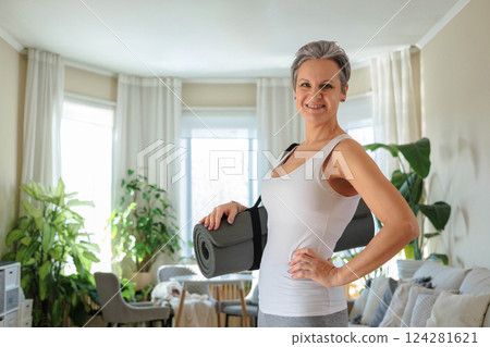 Smiling mature gray haired sport woman with yoga roll mat posing 124281621